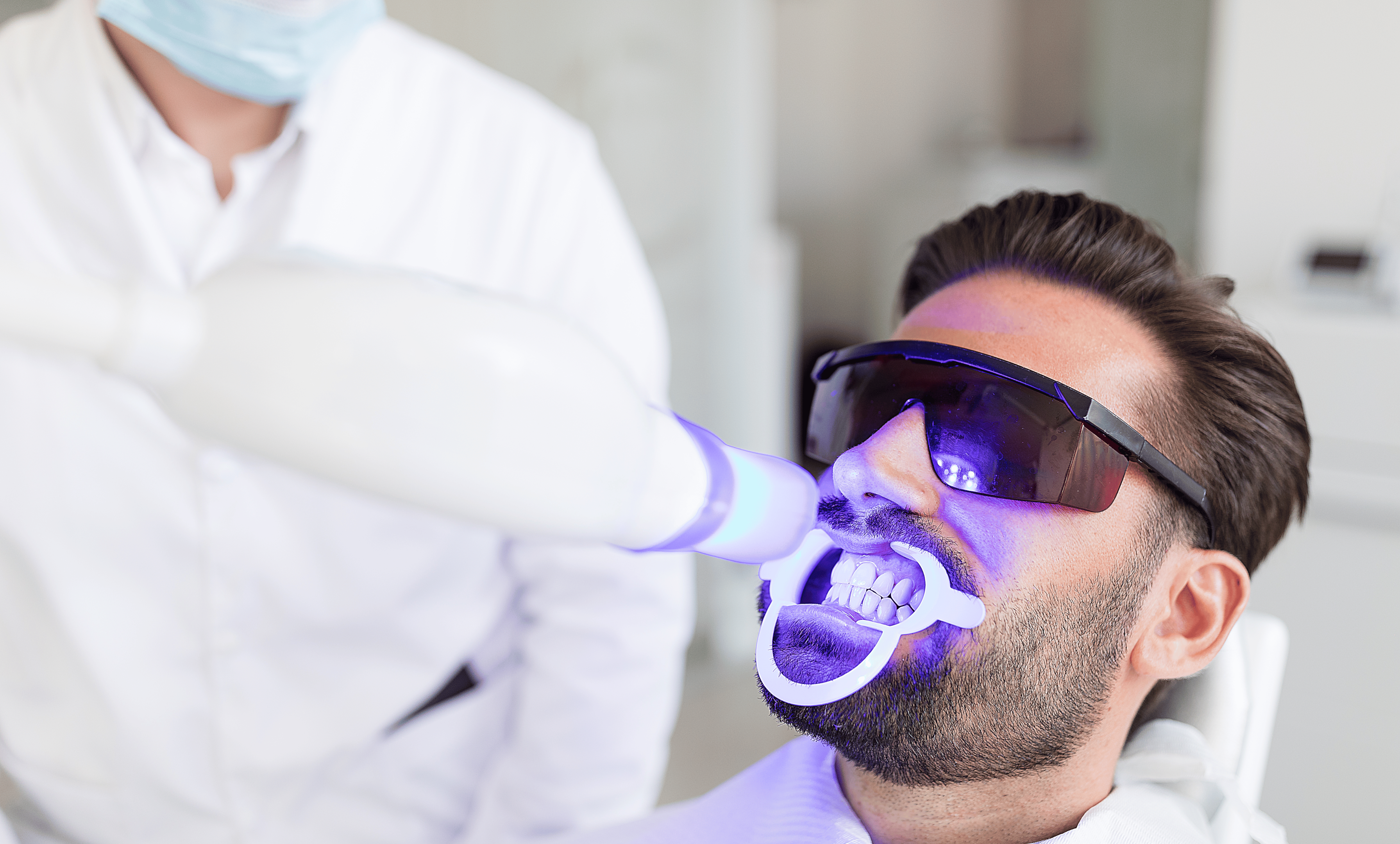 Tannlege som bruker lys for å bleke tennene til en mann