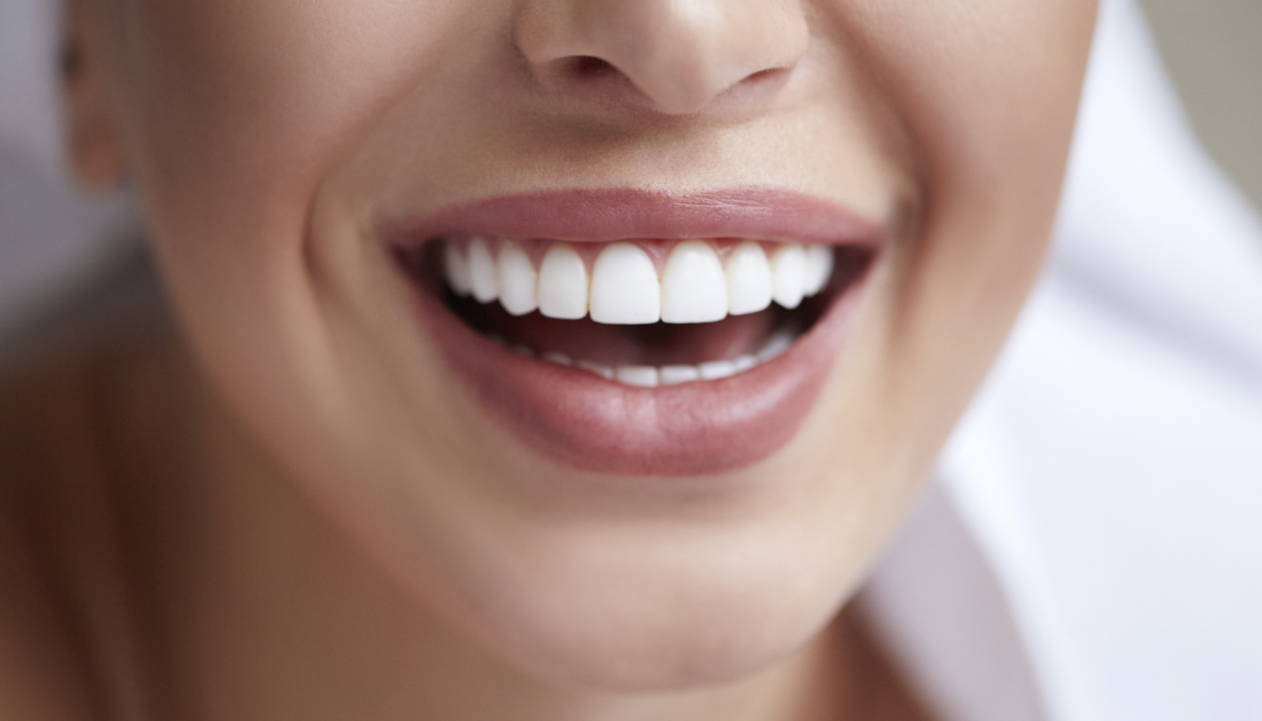 En kvinne smiler med et vakkert, hvitt smil som viser et sunt og strålende tannsett.